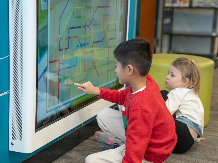 Two children engaging with a large interactive touch screen